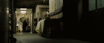 Movie still from “The Taking of Pelham 123” (2009), directed by Tony Scott – A table with a white cloth on top of it in a dark room; Wide shot, High angle