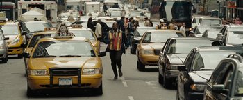 Movie still from “The Taking of Pelham 123” (2009), directed by Tony Scott – A man walking across a busy street with a bunch of taxis; Wide shot, Over the shoulder angle