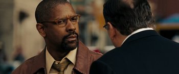 Movie still from “The Taking of Pelham 123” (2009), directed by Tony Scott – A man wearing a leather jacket and a tie talking to another man wearing glasses; Close Up shot, Over the shoulder angle