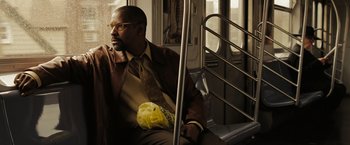 Movie still from “The Taking of Pelham 123” (2009), directed by Tony Scott – A man sitting on a bus with a yellow bag; Medium shot, Over the shoulder angle