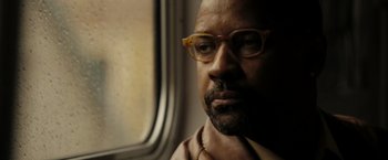 Movie still from “The Taking of Pelham 123” (2009), directed by Tony Scott – A person wearing glasses near a window; Close Up shot, Low angle