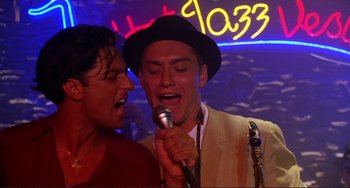 Movie still from “The Talented Mr. Ripley” (1999), directed by Anthony Minghella – Two men sing into a microphone in front of neon lights; Close Up shot, Low angle