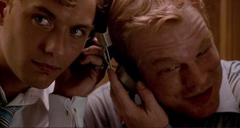 Movie still from “The Talented Mr. Ripley” (1999), directed by Anthony Minghella – A man is talking on a cell phone while another man looks on; Close Up shot, Low angle