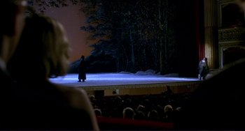 Movie still from “The Talented Mr. Ripley” (1999), directed by Anthony Minghella – A person standing on a stage in front of an audience at night; Extreme Wide shot, Over the shoulder angle