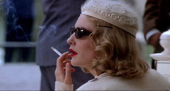 Movie still from “The Talented Mr. Ripley” (1999), directed by Anthony Minghella – A woman with a cigarette in her mouth and wearing a hat; Close Up shot, Low angle
