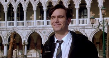 Movie still from “The Talented Mr. Ripley” (1999), directed by Anthony Minghella – A man wearing a suit and tie standing in front of a building; Close Up shot, Low angle