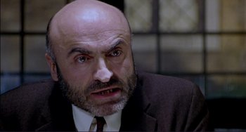 Movie still from “The Talented Mr. Ripley” (1999), directed by Anthony Minghella – A man with a bald head wearing a suit and tie; Close Up shot, Low angle