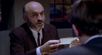 Movie still from “The Talented Mr. Ripley” (1999), directed by Anthony Minghella – A man in a suit and tie holding a piece of paper; Close Up shot, Over the shoulder angle