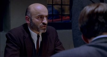 Movie still from “The Talented Mr. Ripley” (1999), directed by Anthony Minghella – A man in a suit and tie sitting in front of another man in a suit; Close Up shot, Over the shoulder angle