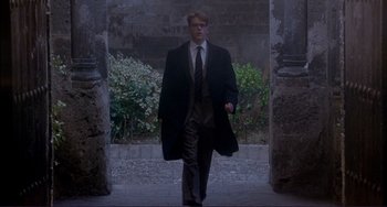 Movie still from “The Talented Mr. Ripley” (1999), directed by Anthony Minghella – A man in a suit and tie walking through an archway; Wide shot, Low angle