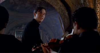 Movie still from “The Talented Mr. Ripley” (1999), directed by Anthony Minghella – A man holding a violin in front of another man; Close Up shot, Over the shoulder angle