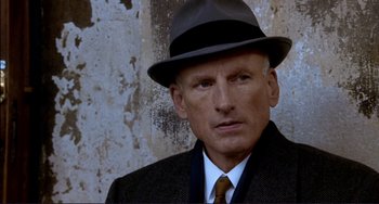 Movie still from “The Talented Mr. Ripley” (1999), directed by Anthony Minghella – An older man wearing a suit and a hat; Close Up shot, High angle