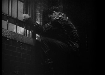 Movie still from “The Talk of the Town” (1942), directed by George Stevens – A man in black jacket leaning on a window ledge; Medium shot, Low angle
