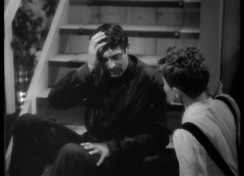 Movie still from “The Talk of the Town” (1942), directed by George Stevens – A man sitting next to another man on a staircase; Medium shot, High angle