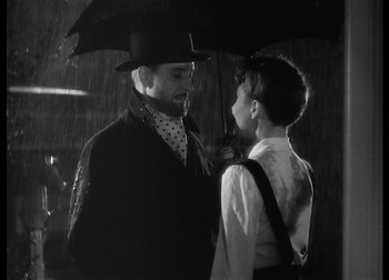 Movie still from “The Talk of the Town” (1942), directed by George Stevens – A man and a boy standing under an umbrella; Medium shot, Low angle