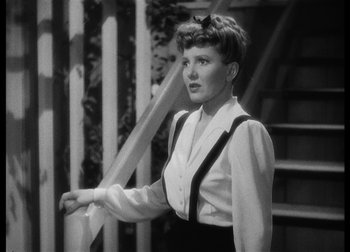Movie still from “The Talk of the Town” (1942), directed by George Stevens – A black - and - white photo of a woman standing next to stairs; Medium shot, Low angle
