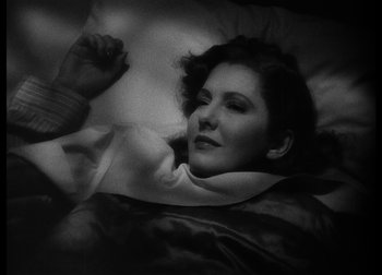 Movie still from “The Talk of the Town” (1942), directed by George Stevens – A black and white photo of a woman laying in a bed; Close Up shot, High angle
