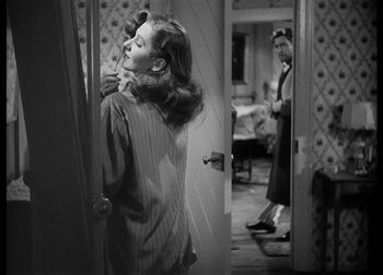 Movie still from “The Talk of the Town” (1942), directed by George Stevens – A woman is standing in a room holding a phone; Medium shot, Over the shoulder angle
