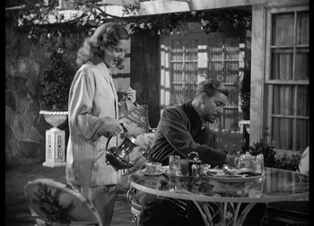Movie still from “The Talk of the Town” (1942), directed by George Stevens – An old photo of a man and a woman at an outdoor table; Medium shot, Over the shoulder angle