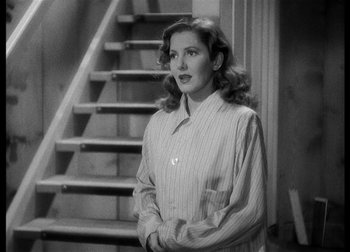 Movie still from “The Talk of the Town” (1942), directed by George Stevens – A black and white photo of a woman standing in front of stairs; Medium shot, High angle
