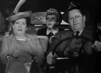 Movie still from “The Talk of the Town” (1942), directed by George Stevens – An old photo of a man and two women driving a car; Medium shot, High angle