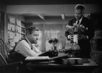 Movie still from “The Talk of the Town” (1942), directed by George Stevens – A man sitting at a table with a flower pot; Medium shot, High angle