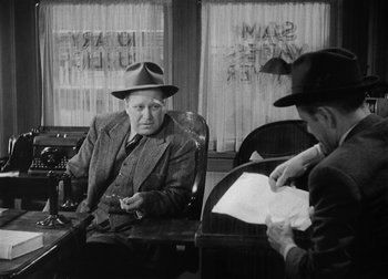 Movie still from “The Talk of the Town” (1942), directed by George Stevens – A man in a suit and hat sitting next to another man in a hat; Medium shot, Over the shoulder angle
