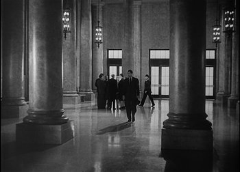 Movie still from “The Talk of the Town” (1942), directed by George Stevens – A black and white photo of a group of people walking in a building; Extreme Wide shot, Low angle