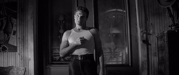 Movie still from “The Tarnished Angels” (1957), directed by Douglas Sirk – A black and white photo of a man standing in front of a window; Medium shot, Low angle