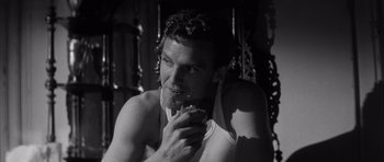 Movie still from “The Tarnished Angels” (1957), directed by Douglas Sirk – A black and white photo of a man eating a donut; Close Up shot, High angle