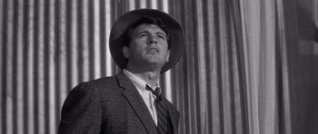 Movie still from “The Tarnished Angels” (1957), directed by Douglas Sirk – A black and white photo of a man wearing a suit and a hat; Close Up shot, Low angle