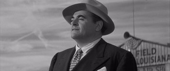 Movie still from “The Tarnished Angels” (1957), directed by Douglas Sirk – A man wearing a suit and a hat is looking up; Close Up shot, Low angle