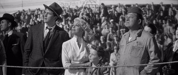 Movie still from “The Tarnished Angels” (1957), directed by Douglas Sirk – An old photo of a man and a woman and a boy in front of a crowd; Medium shot, Low angle