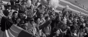 Movie still from “The Tarnished Angels” (1957), directed by Douglas Sirk – A group of people sitting in the stands at a sporting event; Medium shot, High angle