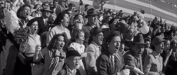 Movie still from “The Tarnished Angels” (1957), directed by Douglas Sirk – A group of people that are sitting in the bleachers; Medium shot, High angle