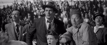 Movie still from “The Tarnished Angels” (1957), directed by Douglas Sirk – An old photo of a man and a boy in a crowd; Medium shot, Low angle