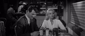 Movie still from “The Tarnished Angels” (1957), directed by Douglas Sirk – A man and a woman sitting at a table; Medium shot, Over the shoulder angle