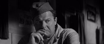 Movie still from “The Tarnished Angels” (1957), directed by Douglas Sirk – A man wearing a military hat and a shirt; Close Up shot, Low angle