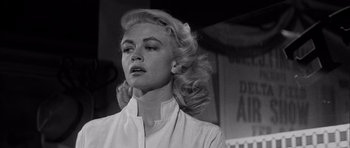 Movie still from “The Tarnished Angels” (1957), directed by Douglas Sirk – A black and white photo of a woman with long blonde hair; Close Up shot, Low angle