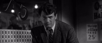 Movie still from “The Tarnished Angels” (1957), directed by Douglas Sirk – Black and white photograph of a man wearing a suit and tie; Close Up shot, Over the shoulder angle