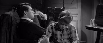 Movie still from “The Tarnished Angels” (1957), directed by Douglas Sirk – A woman and a boy sitting next to each other; Medium shot, High angle