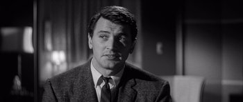 Movie still from “The Tarnished Angels” (1957), directed by Douglas Sirk – Black and white photograph of a man wearing a suit and tie; Close Up shot, Over the shoulder angle