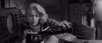 Movie still from “The Tarnished Angels” (1957), directed by Douglas Sirk – A black and white photo of a woman pouring a glass of red wine; Close Up shot, Low angle
