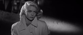 Movie still from “The Tarnished Angels” (1957), directed by Douglas Sirk – A black and white photo of a woman in a trench coat; Close Up shot, Low angle