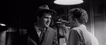 Movie still from “The Tarnished Angels” (1957), directed by Douglas Sirk – A black and white photo of a man in a suit and a hat; Close Up shot, Over the shoulder angle