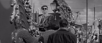 Movie still from “The Tarnished Angels” (1957), directed by Douglas Sirk – An older man wearing a hat and sunglasses; Medium shot, Low angle