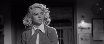Movie still from “The Tarnished Angels” (1957), directed by Douglas Sirk – A black and white photo of a woman with blonde curly hair; Close Up shot, Low angle