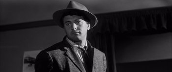 Movie still from “The Tarnished Angels” (1957), directed by Douglas Sirk – A black and white photo of a man wearing a hat; Close Up shot, Low angle