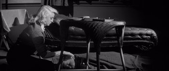 Movie still from “The Tarnished Angels” (1957), directed by Douglas Sirk – A man and a woman laying on a bed under a chair; Medium shot, High angle