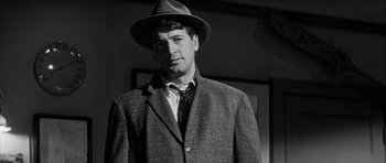 Movie still from “The Tarnished Angels” (1957), directed by Douglas Sirk – A black and white photo of a man wearing a suit and a hat; Close Up shot, Low angle